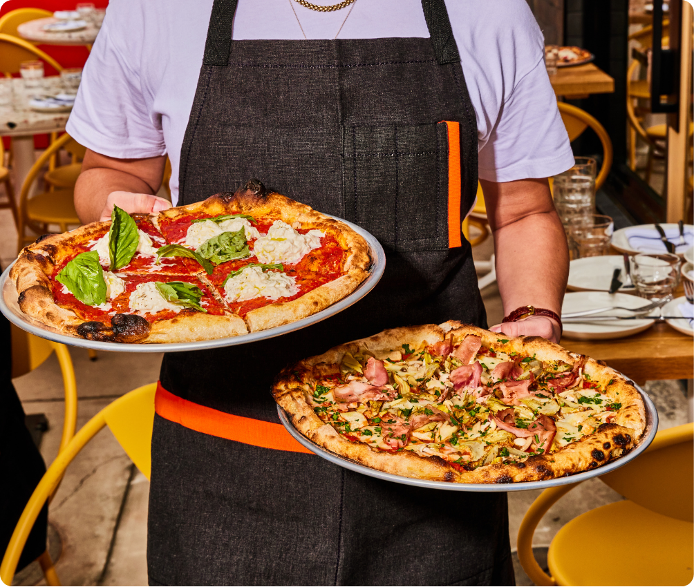 A Delarosa server carrying two Roman-style pizzas